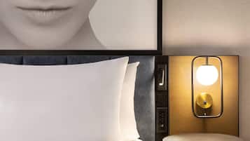Une chambre d’hôtel moderne avec un grand lit, une table ronde et un luminaire fixé au mur.