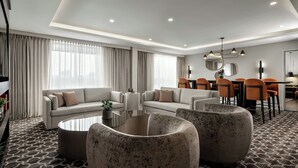 A modern hotel room with a living area, sofa set, coffee table, and dining area with chairs and a table. - Sheraton Toronto Airport Hotel & Conference Centre (Toronto)