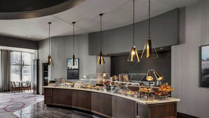 A modern hotel lobby with a curved reception desk, buffet area, and pendant lighting. - Sheraton Toronto Airport Hotel & Conference Centre (Toronto)