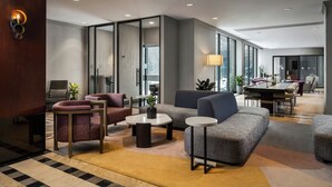 A modern hotel lobby with a checkered floor, seating areas, a dining table, and large windows. - Sheraton Toronto Airport Hotel & Conference Centre (Toronto)