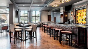 A modern bar area with a long counter, multiple stools, and a television screen. - Sheraton Toronto Airport Hotel & Conference Centre (Toronto)