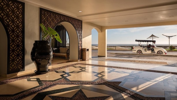A spacious lobby with a large vase, patterned walls, and a view of the beach with a golf cart. - Don Pelayo Pacific Beach (Mazatlán)