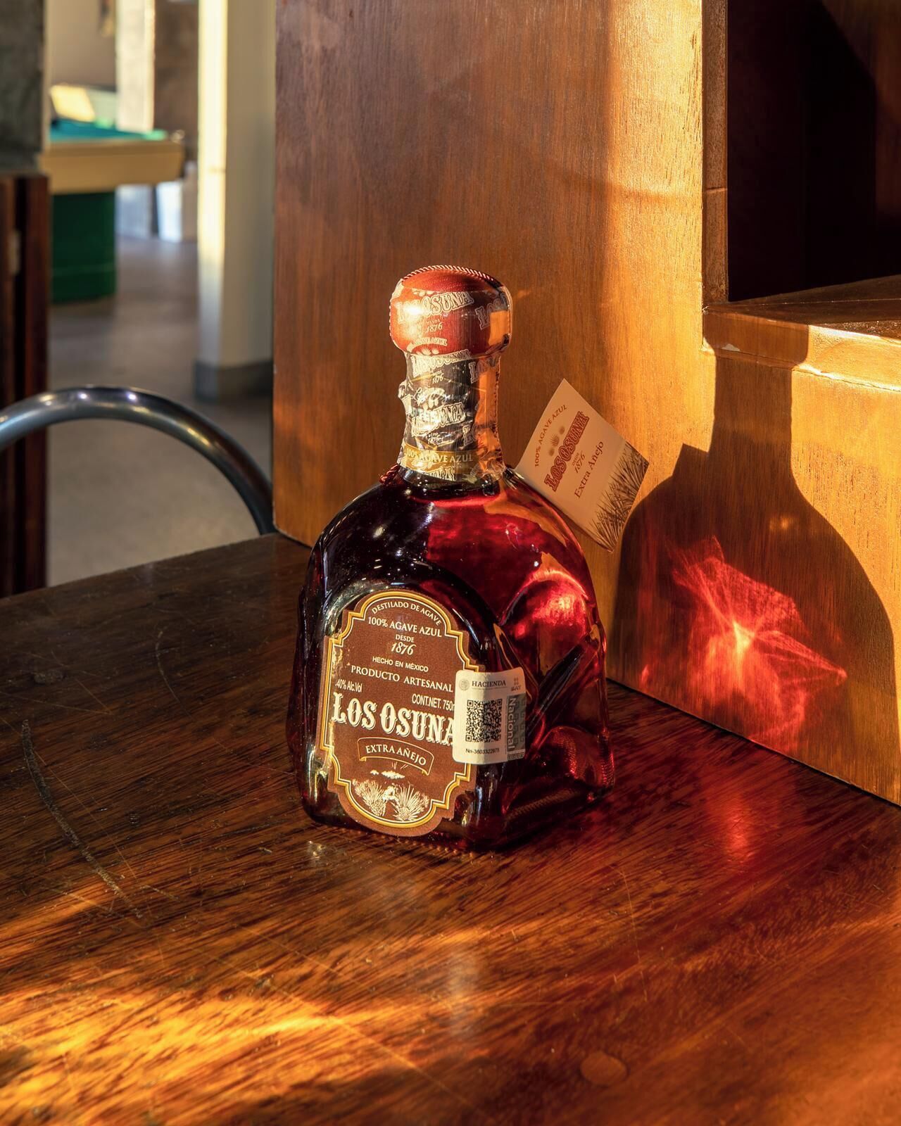 Une bouteille de tequila Los Osuna Extra Añejo posée sur une table en bois.