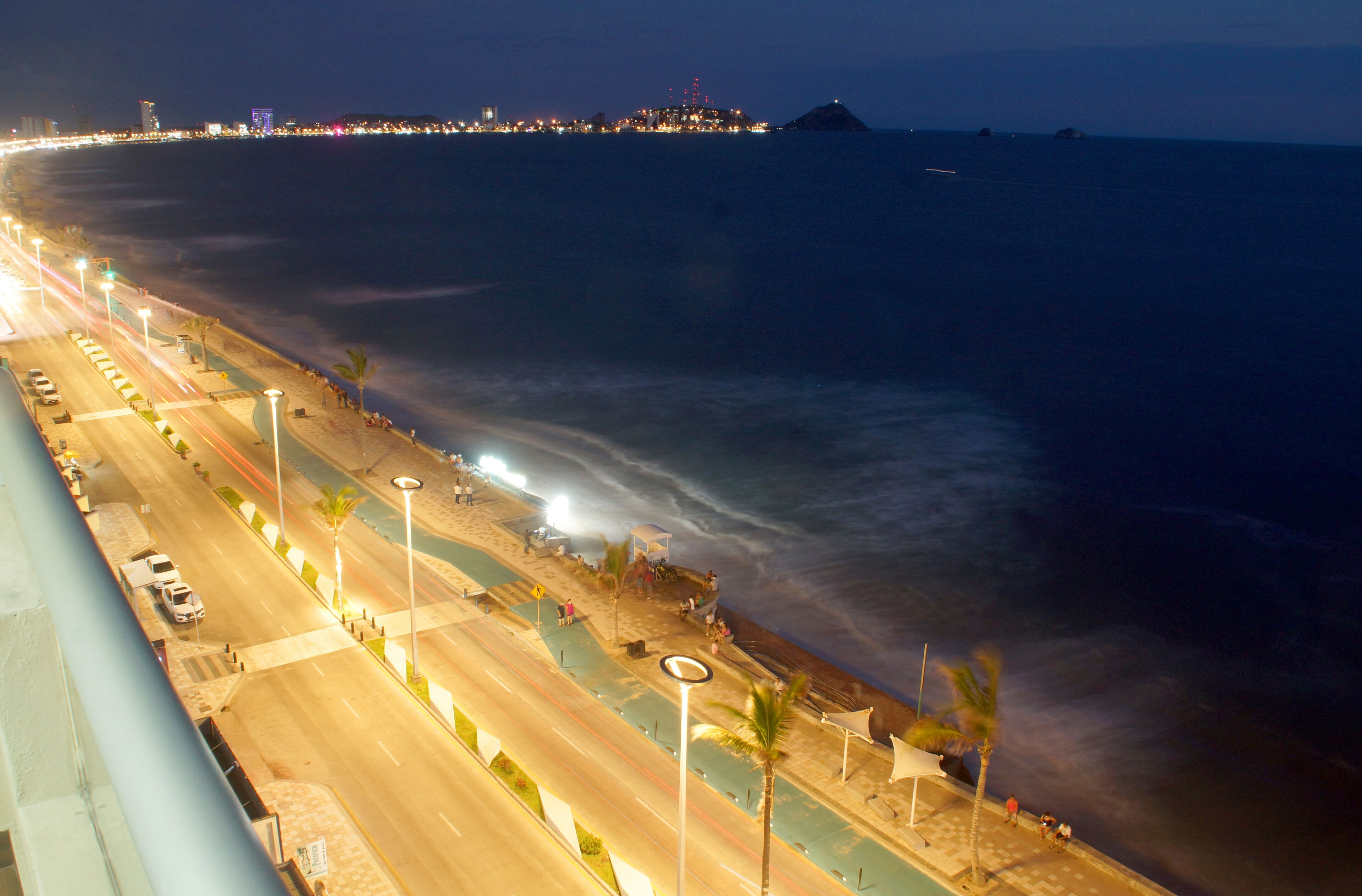 Una carretera costera con una playa a un lado y un paisaje urbano a lo lejos.