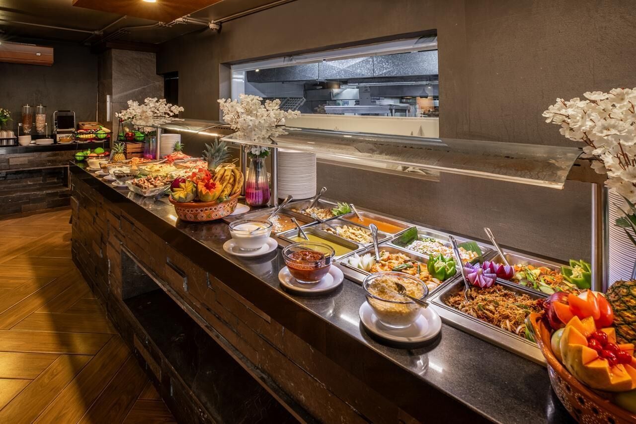 Un buffet proposant une variété de plats, avec une cuisine en arrière-plan.