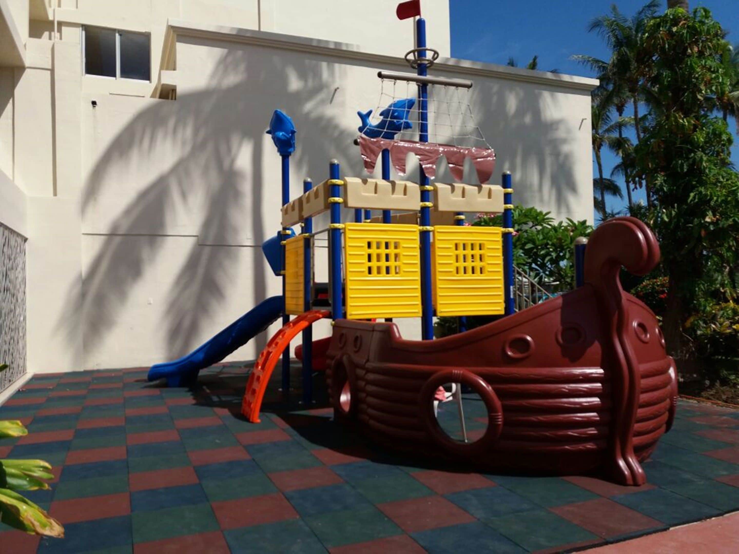 A children's play area with a slide, climbing structures, and a ship-shaped play structure.
