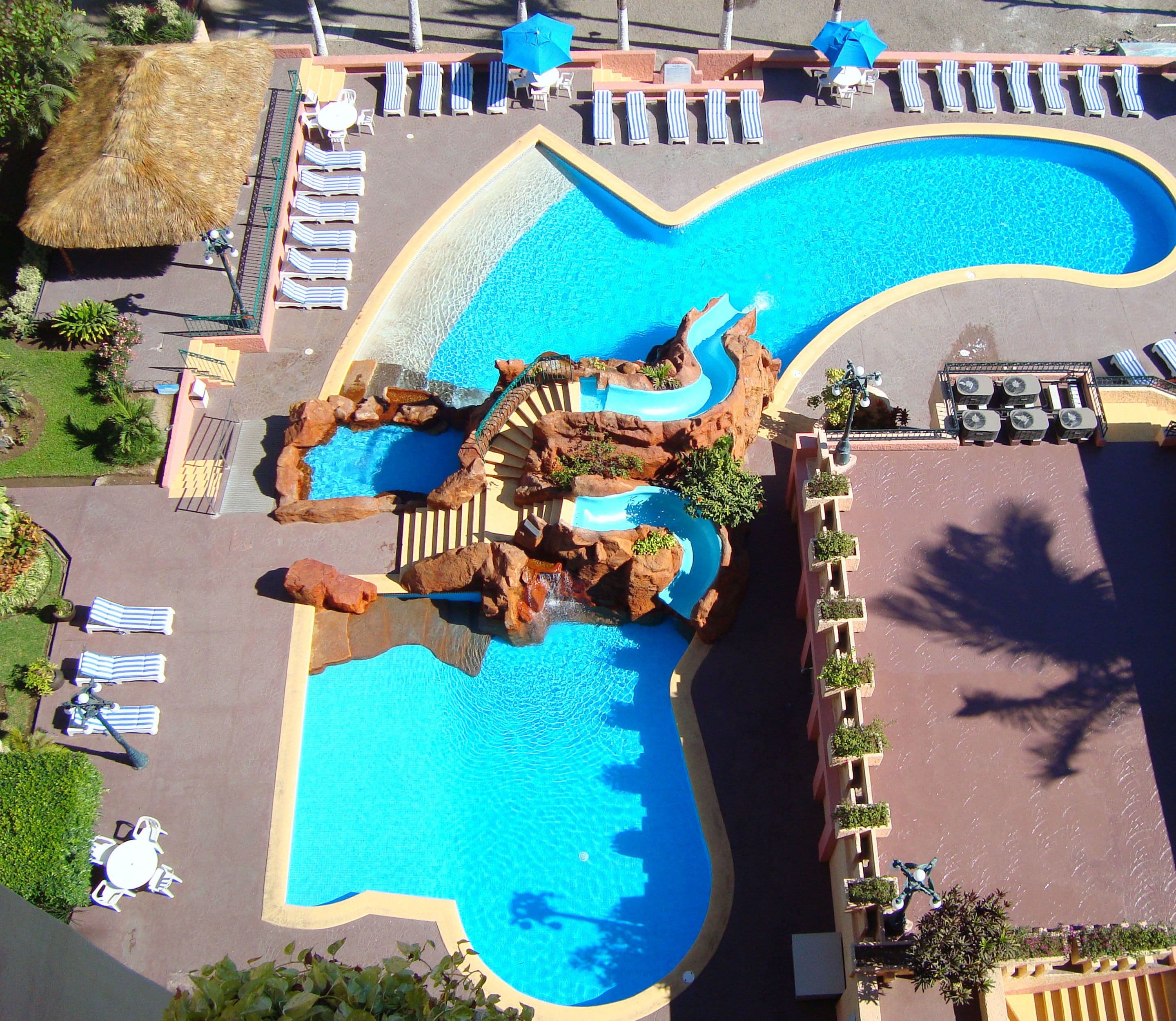 Een buitenzwembad, parasols bij het zwembad en ligstoelen