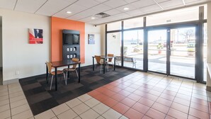 A spacious indoor area with a large window, a television, and a seating arrangement. - Motel 6 Stephenville, TX (Stephenville)