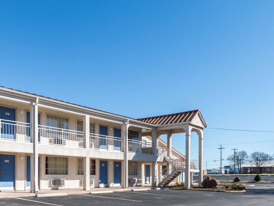 A motel with a two-story structure, a covered walkway, and a parking lot.