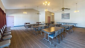 A conference room with multiple tables and chairs, ceiling fans, and hanging lights. - Motel 6 Stephenville, TX (Stephenville)