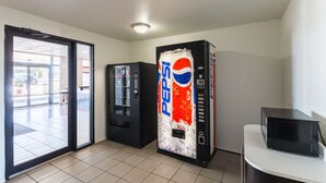 A room with a vending machine, a microwave, and a sliding glass door leading to an outdoor area. - Motel 6 Stephenville, TX (Stephenville)