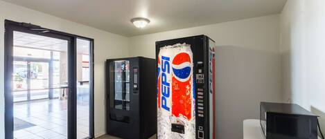 A room with a vending machine, a microwave, and a sliding glass door leading to an outdoor area.