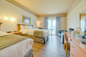 Two single beds with matching headboards and a nightstand sit in a clean and functional room with a desk and chair near the window.