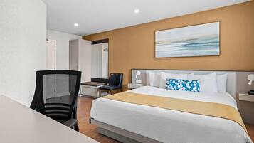 Habitació d'hotel amb un llit gran, un escriptori, una cadira i un quadre a la paret.