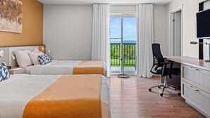 A hotel room with two beds, a desk, a chair, a TV, and a balcony with a view. - Days Inn by Wyndham Riviere-Du-Loup (Rivière-du-Loup)