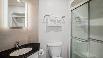 Een badkamer met een wit wastafelmeubel, toilet en een douchecabine van glas.