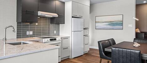 Una cocina moderna con una isla central, electrodomésticos integrados y un comedor con mesa y sillas.