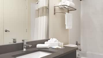 A modern bathroom with a dual sink vanity, a large mirror, a towel rack, and a shower.