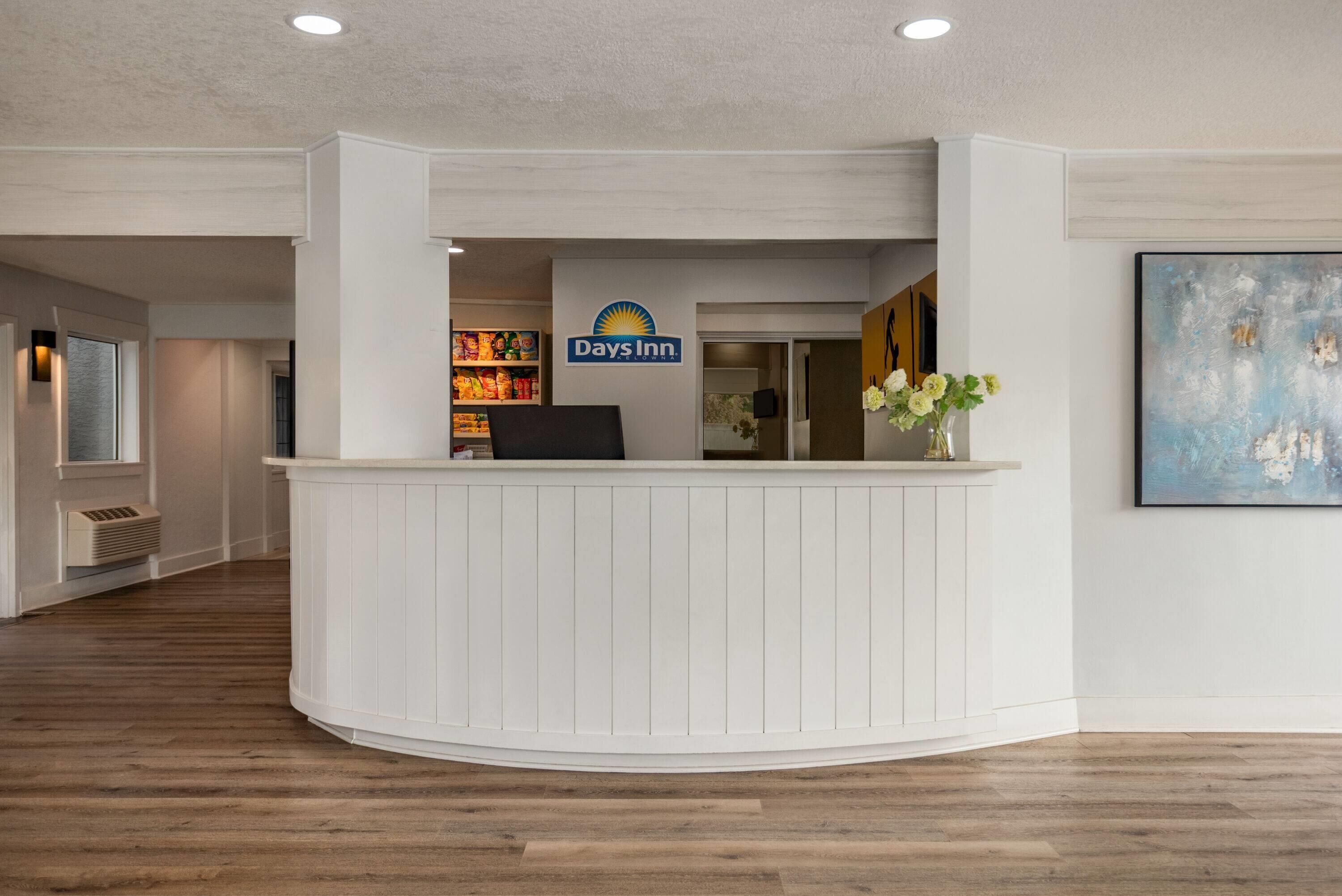 A reception area with a white reception desk, a sign for Days Inn, and a painting on the wall.