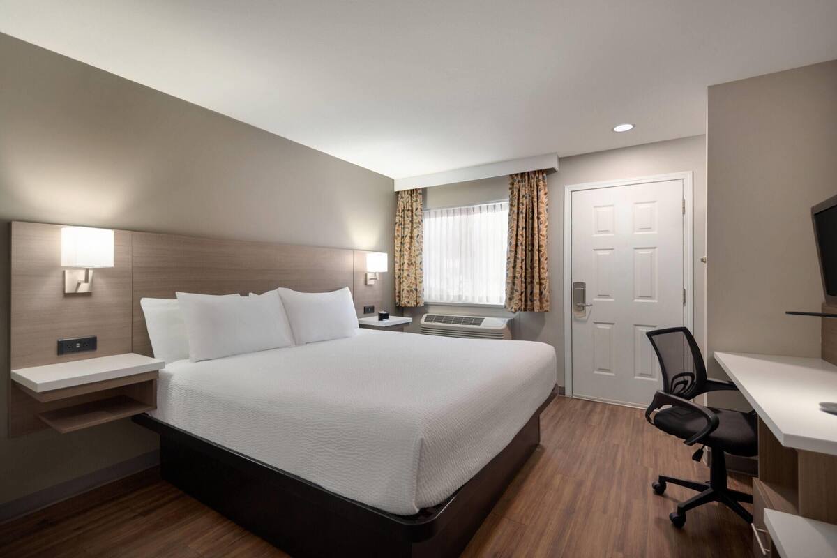 A hotel room with a large bed, bedside tables, a desk, and a chair.