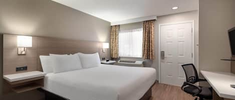 A hotel room with a large bed, bedside tables, a desk, and a chair.