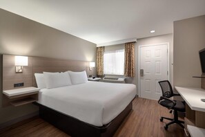 Une chambre d’hôtel avec un grand lit, des tables de chevet, un bureau et une chaise.