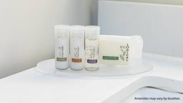 Een badkamer met een witte wasbak en drie flessen L'ECÔGICAL producten: lotion, conditioner en shampoo.