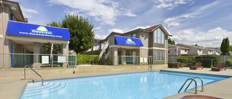 A swimming pool with lounge chairs, a Days Inn sign, and a covered walkway.