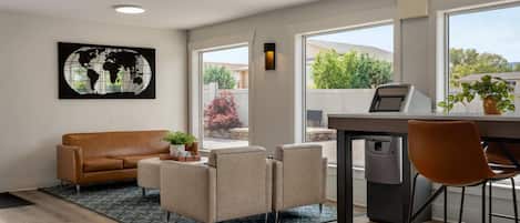 A modern living room with a brown leather sofa, beige armchairs, a coffee table, and a world map artwork on the wall.