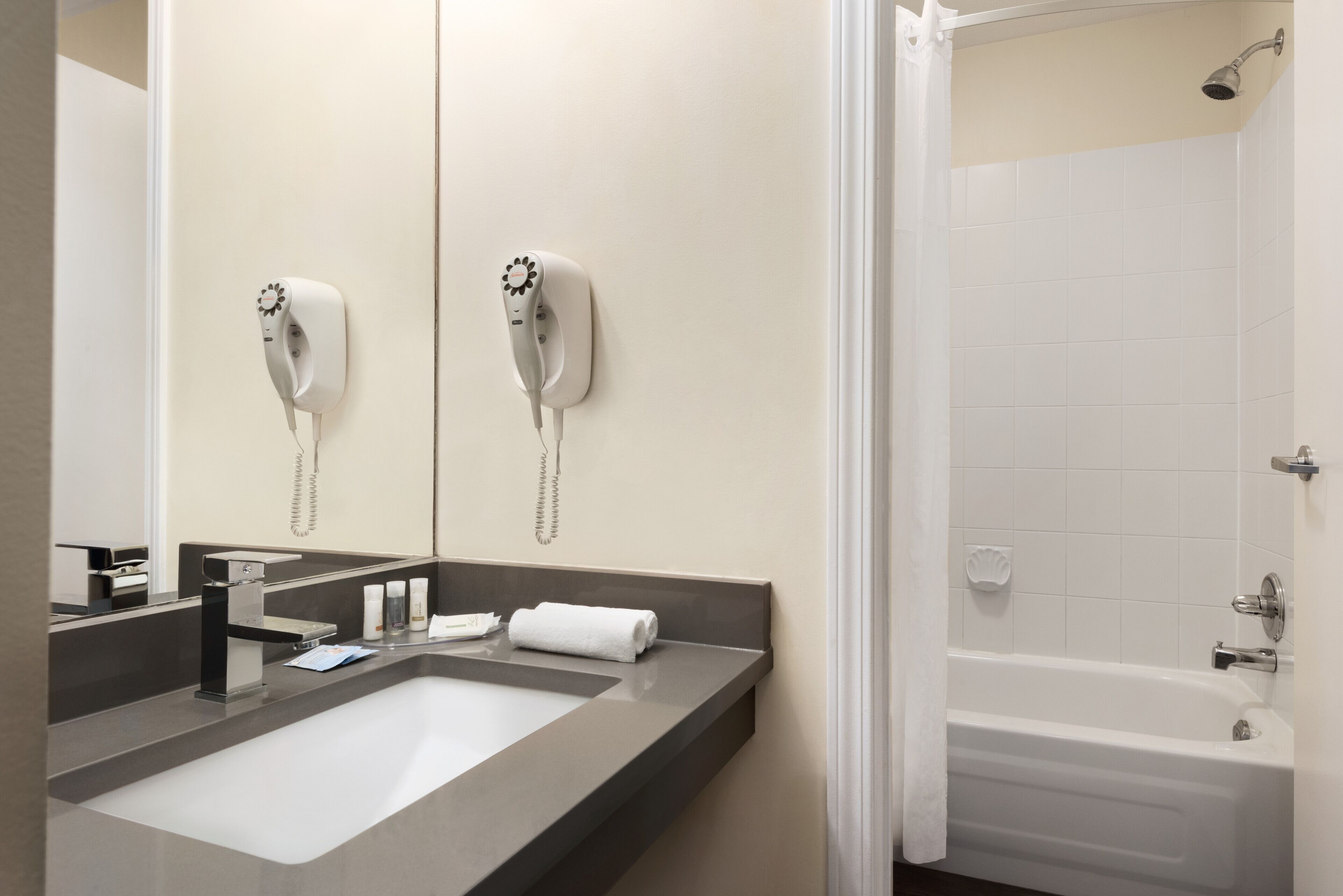 Un baño con lavamanos, espejo, toalla y ducha.