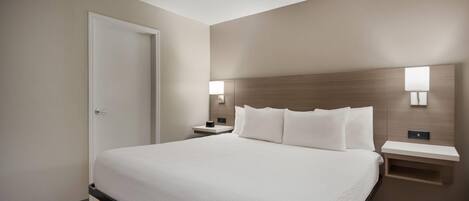 Una habitación de hotel con una cama grande, mesitas de noche y un buró.