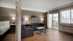 Habitación de hotel con cama, sofá, mesa de centro y un cuadro en la pared.