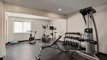 Uma academia com equipamentos de ginástica, um banco e halteres.