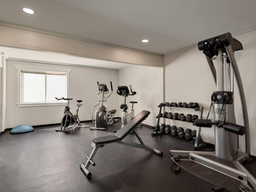 Uma academia com equipamentos de ginástica, um banco e halteres.