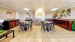 A dining area with a central table surrounded by chairs, a kitchen counter, and a bulletin board. - Hotel Eloy/ Casa Grande Near I-10 (Eloy)
