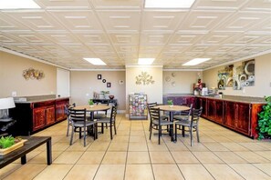 A dining area with a central table surrounded by chairs, a kitchen counter, and a bulletin board. - Hotel Eloy/ Casa Grande Near I-10 (Eloy)