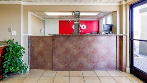 A reception area with a red wall, a stone pillar, and a computer monitor. - Hotel Eloy/ Casa Grande Near I-10 (Eloy)