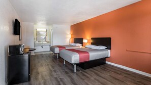 Une chambre d’hôtel avec deux lits, un bureau et une télévision.