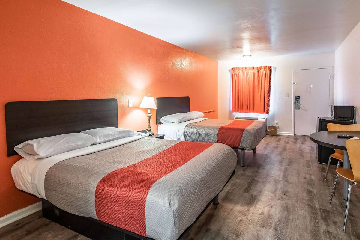 A hotel room with two beds, a desk, and a television.