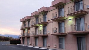 Ein mehrstöckiges Hotel mit Balkonen, Klimaanlagen und einem Parkplatz.