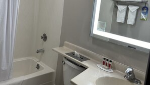 Ein Badezimmer mit Dusche, Toilette, Waschbecken und einem Spiegel mit Handtuchhalter.