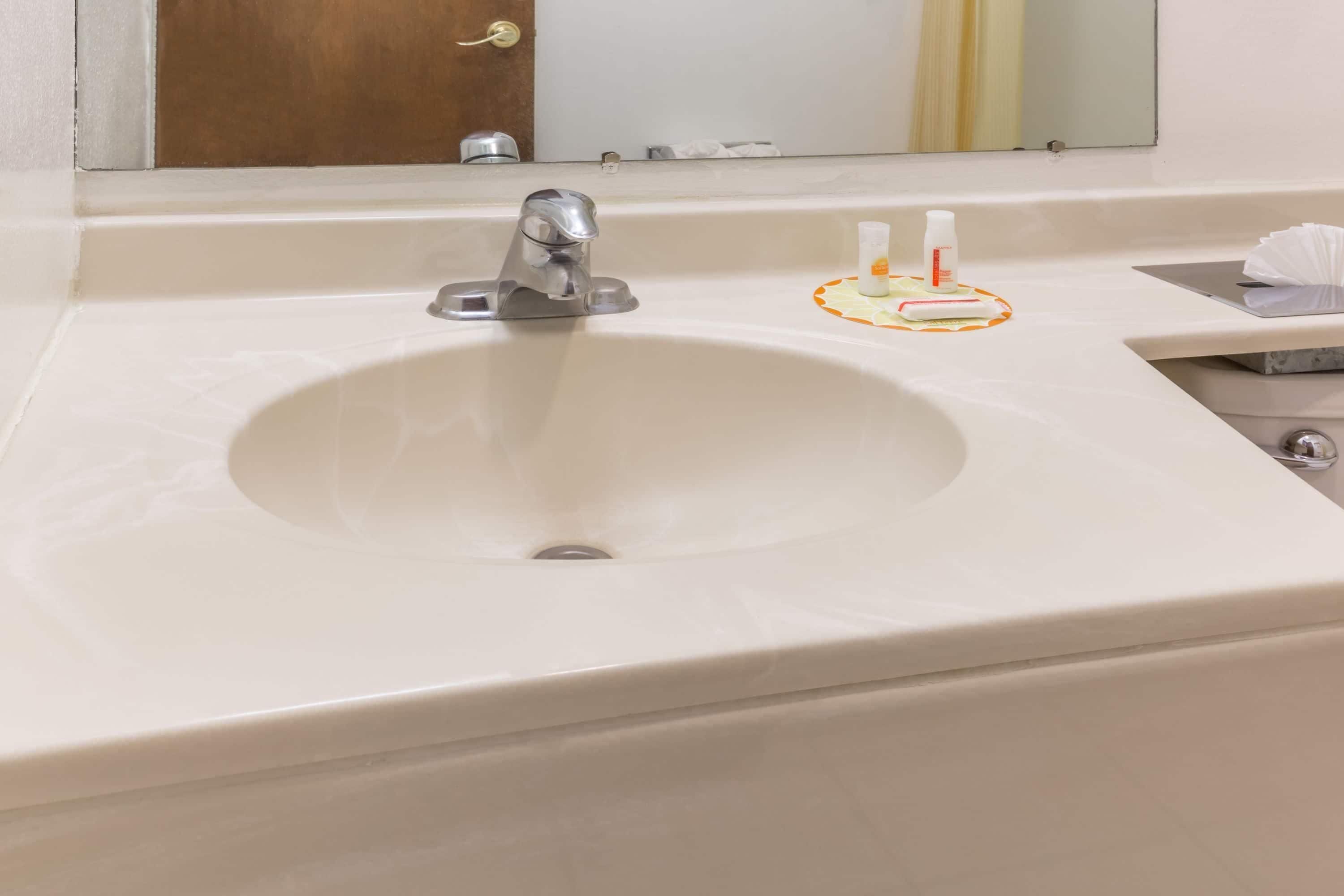 A bathroom sink with a mirror above it, a faucet, and a towel rack to the right.