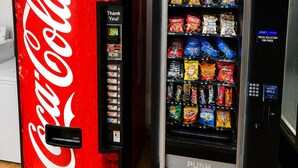 Zwei Getränkeautomaten, einer mit Coca-Cola-Logo, der andere mit verschiedenen Snacks.