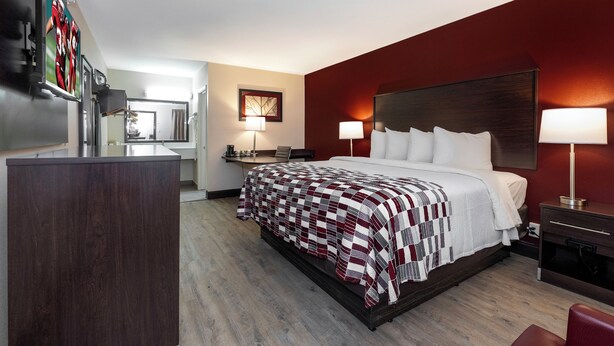 Ein Hotelzimmer mit einem großen Bett, zwei Nachttischen, einem Schreibtisch und einem Sessel.