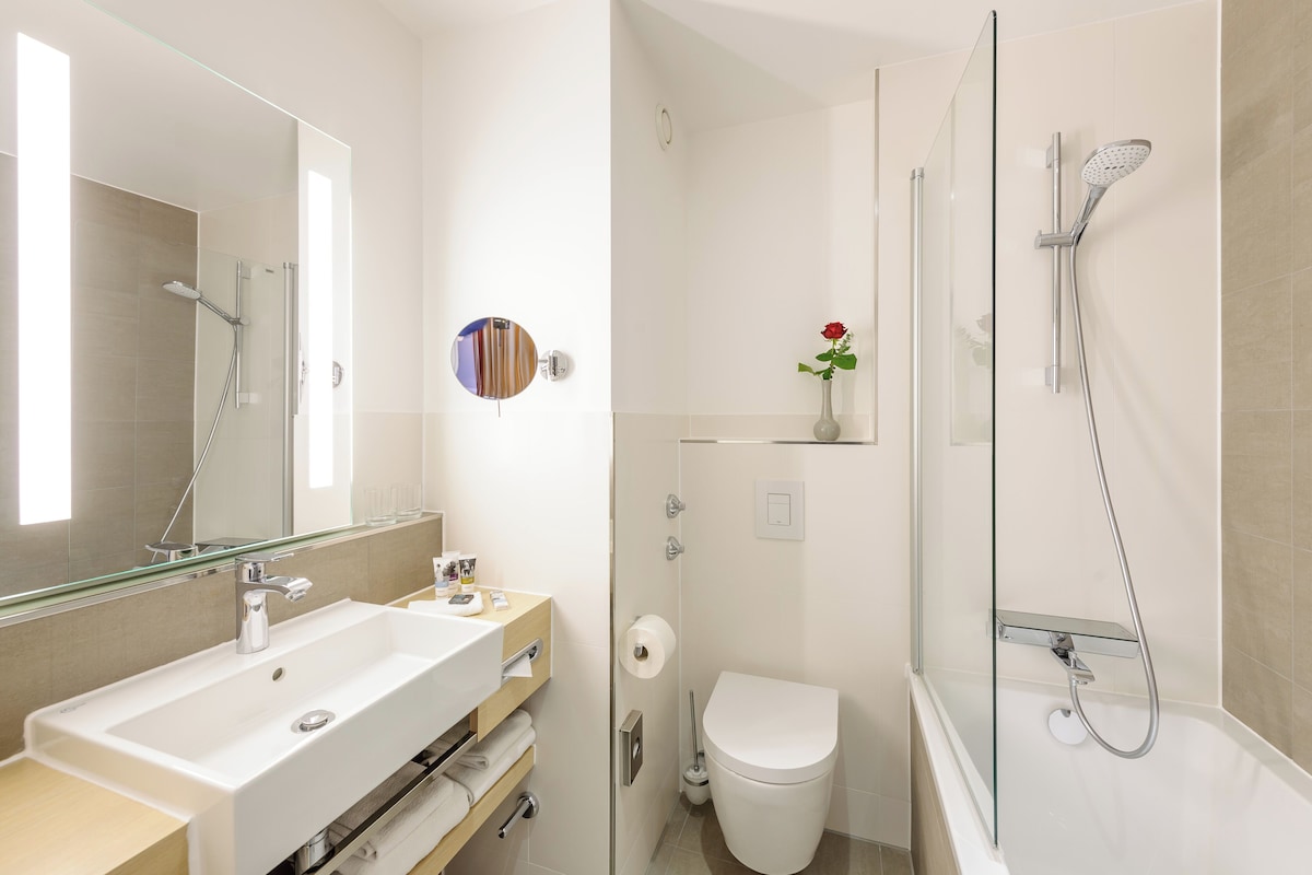 Een moderne badkamer met een groot wastafel, toilet en douchecabine met glazen wanden.