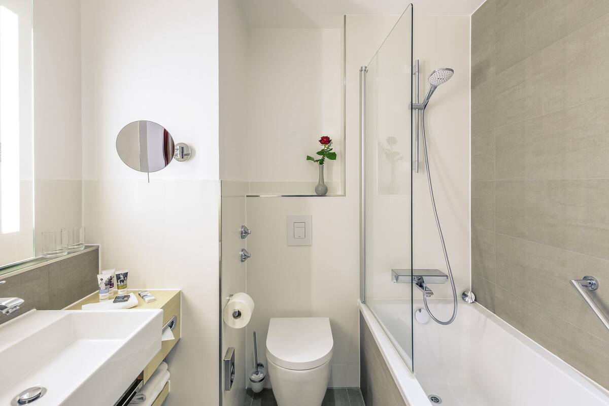 Un baño moderno con ducha acristalada, lavamanos blanco y un inodoro.
