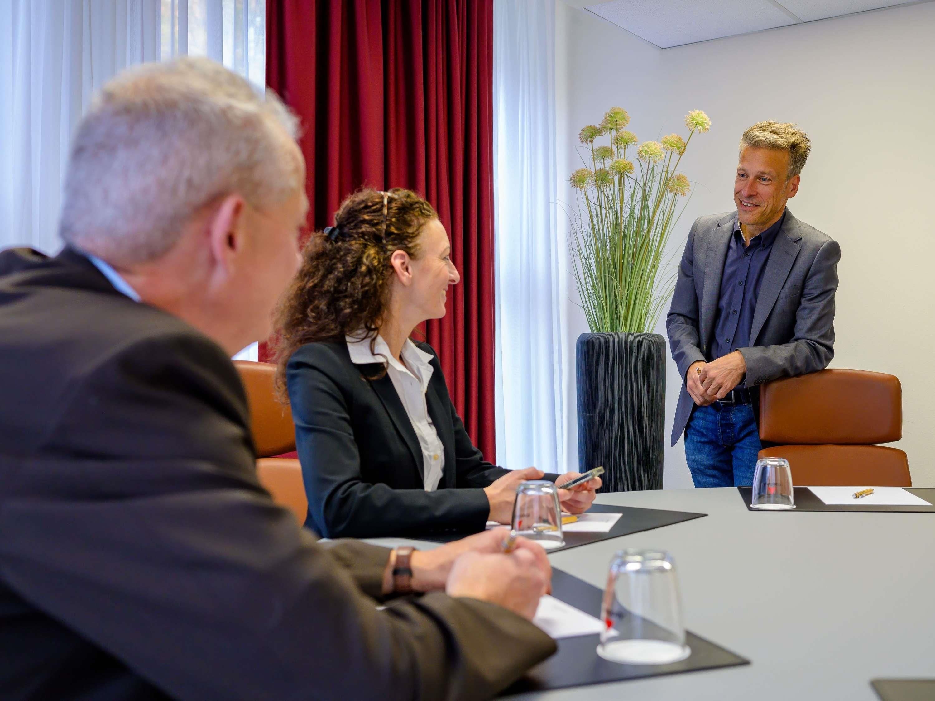A conference room with a table, chairs, and a potted plant.