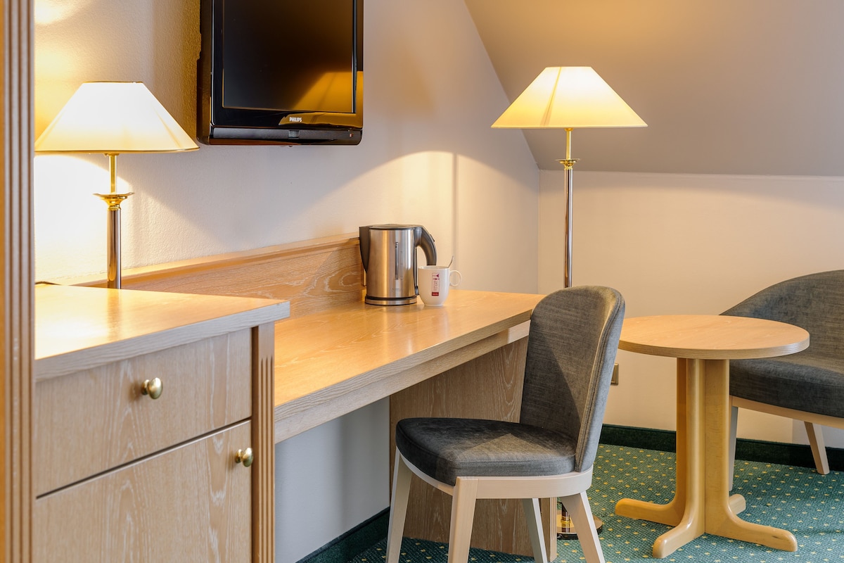 Een hotelkamer met een houten bureau, twee lampen, een televisie en een stoel.