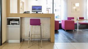 A reception area with a computer monitor, a printer, and a seating area with chairs. - Mercure Hotel Erfurt Altstadt (Erfurt)