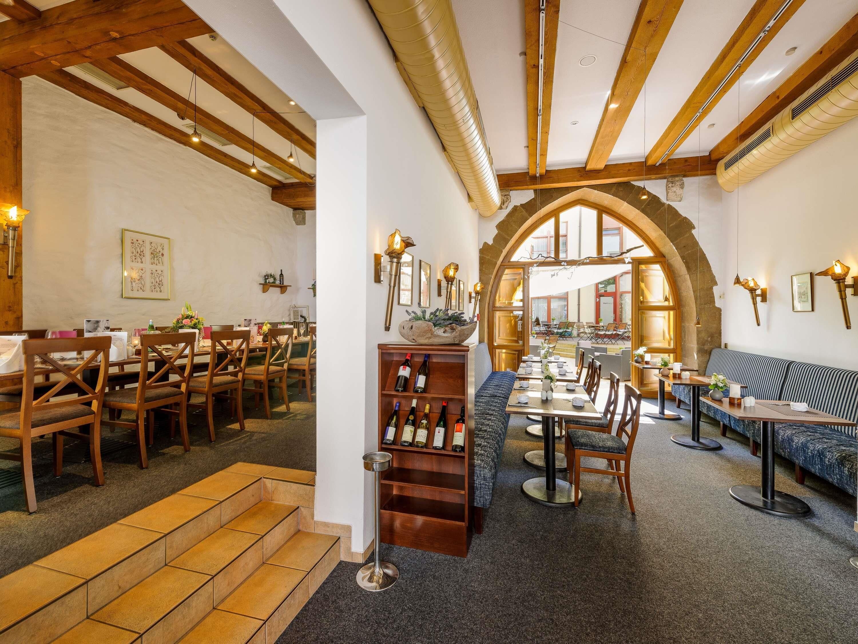 A restaurant with wooden beams, a stone archway, and a cozy seating area.